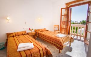 イオス島 チョーラにあるVillage Twinsのベッド2台とバルコニーが備わるホテルルームです。