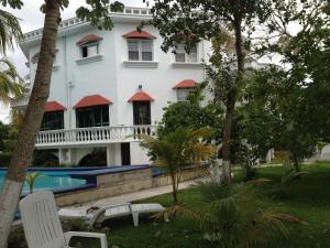 a large white building with a swimming pool and trees at Mansion Giahn Bed & Breakfast in Cancún