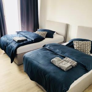 2 bedden in een slaapkamer met blauwe lakens en handdoeken bij Boardinghouse BeOne in Villingen-Schwenningen