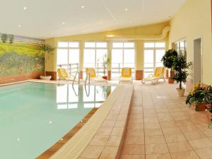 einen Pool in einem Hotel mit gelben Stühlen in der Unterkunft Pension Zum Riedensee in Kühlungsborn