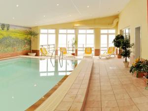 - une piscine dans un hôtel avec des chaises jaunes dans l'établissement Pension Zum Riedensee, à Kühlungsborn