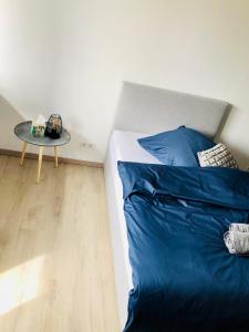 um quarto com uma cama com lençóis azuis e uma mesa em Boardinghouse BeOne em Villingen-Schwenningen