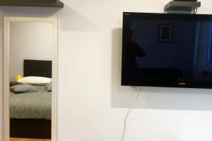 TV de pantalla plana colgada en una pared junto a un dormitorio en Apartman Loen, en Zagreb