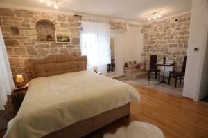 - une chambre avec un grand lit et un mur en pierre dans l'établissement Apartments Nikolla, à Split