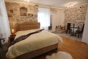 - une chambre avec un lit et un mur en pierre dans l'établissement Apartments Nikolla, à Split