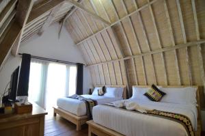 a bedroom with two beds and a large window at Lavella Villas Kuta Lombok in Kuta Lombok