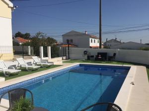 a swimming pool in a yard with chairs and a house at Casa Vila Sao & Pompeia in Sesimbra