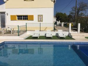 a swimming pool with two lounge chairs and a house at Casa Vila Sao & Pompeia in Sesimbra