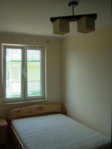 a bedroom with a bed and a window at Los Reyes in Krynica Morska