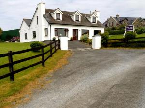 a white house with a fence in front of it at Cnoc Breac B&B in Cleggan