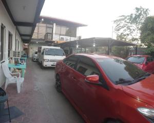 un coche rojo estacionado en un estacionamiento con un paraguas en Prince Transient house en San José