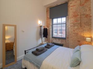 a bedroom with a bed and a brick wall at Apartment 16 Broadway House in Nottingham