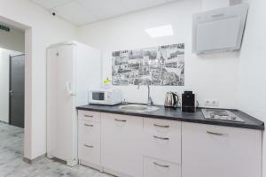 eine weiße Küche mit einer Spüle und einem Kühlschrank in der Unterkunft SkyHome na Nauky in Kiew