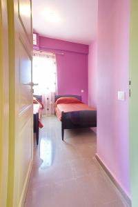 sypialnia z łóżkiem i fioletowymi ścianami w obiekcie Darmani Spyros Apartments w mieście Mantoúkion