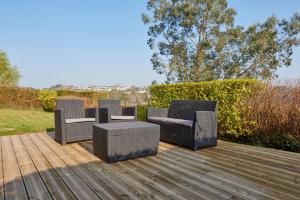 quatro cadeiras de vime e uma mesa num deque de madeira em Jean Bart - proximité centre - 2 chambres 90 m2 avec jardin em Saint-Brieuc