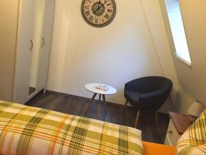 a room with a chair and a clock on the wall at Ferienwohnung Hotel Glockenhof in Eltville