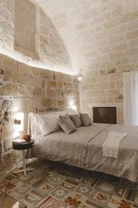 
a bed in a room with a wall made of bricks at Cenobio Hotel in Matera
