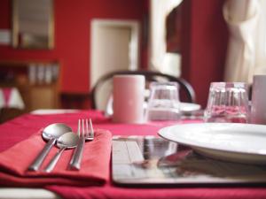 a table with a red table cloth and utensils on it at The Coach House in Canterbury