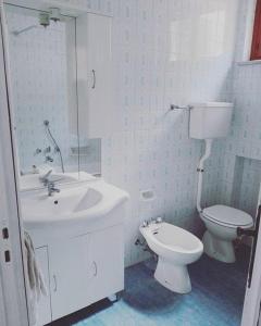 a white bathroom with a toilet and a sink at Casa Flora in Diano Marina