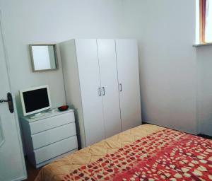 a bedroom with a bed and a desk with a television at Casa Flora in Diano Marina