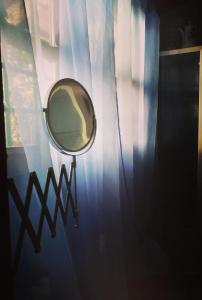 een spiegel die aan een raam hangt met een gordijn bij La Casa di Marla in Sirmione +5 foto's