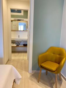 a yellow chair in a room with a bathroom at Una terrazza sul mare - Balzi Rossi in Ventimiglia
