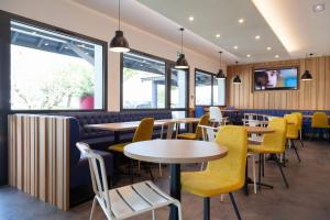 a restaurant with tables and yellow chairs at Kyriad Niort-Espace MendesFrance in Niort