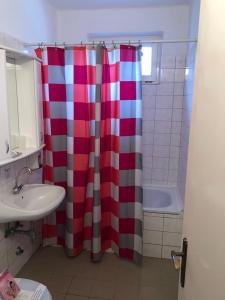 a bathroom with a red and white shower curtain at Hotel Flóra** in Orosháza