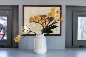 a white vase with yellow flowers in front of a picture at Isola Bella Apartments - Via del Voltone in Stresa
