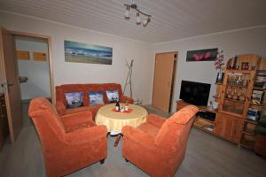 ein Wohnzimmer mit 2 orangenen Stühlen und einem Tisch in der Unterkunft Ferienwohnung Sundhagen in Reinberg