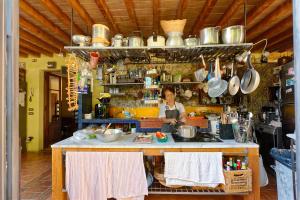 a woman in a kitchen with a counter with pots and pans at Le stanze del Casale - Maison in Portoferraio