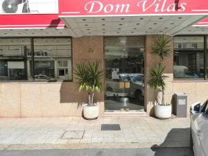 a store front with two palm trees in front of it at Hotel Dom Vilas in Braga