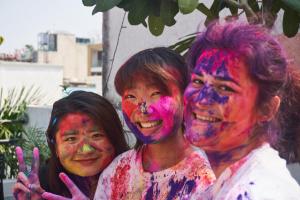 three women covered in paint posing for a picture at The Desire Hostel in New Delhi
