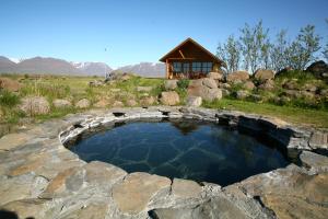 a large stone pool with a stone fireplace at Hestasport Cottages in Varmahlid
