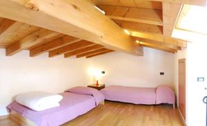 two beds in a room with wooden ceilings at Casa Mary apartments in Tignale +85 photos