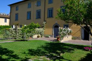 un gran edificio amarillo con un patio con flores en B&B Glicine e Luna, en Cascina