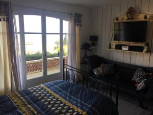 a bedroom with a bed and a tv and a balcony at Villa Kahina in Les Issambres