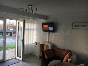 a living room with a couch and a television on the wall at White Lodge in Caernarfon
