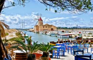 a marina with tables and chairs and a windmill at Casa Anna Maria in Marsala