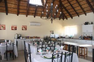 una sala da pranzo con tavoli e sedie e una cucina di Villa Royal Palm a Komatipoort