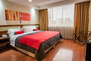 Hotel Libertador في سانتياغو: غرفة نوم بسرير كبير مع بطانية حمراء