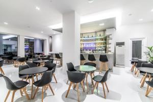 un restaurant avec des tables et des chaises ainsi qu'un bar dans l'établissement Byzantio City Hotel, à Tinos