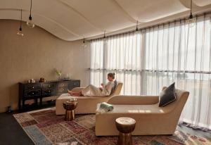 a man sitting on a couch in a living room at Fairmont Ajman in Ajman 