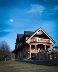 Una gran casa de madera con un porche y una luna en el cielo en Góralska Chata Pieniny, en Krościenko nad Dunajcem