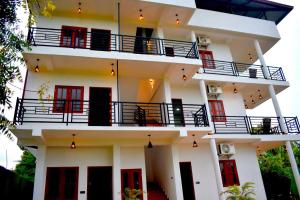 a white building with red doors and balconies at Blue Sky Hotel Yala in Yala