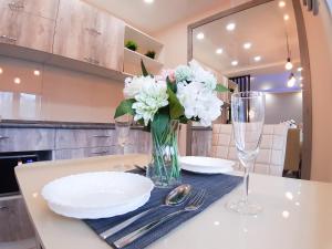 a table with plates and glasses and a vase of flowers at Apartment on Potanina 16 in Ustʼ-Kamenogorsk