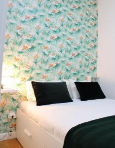 ein Schlafzimmer mit einem Bett mit tropischer Tapete in der Unterkunft FeelCoimbra Apartamento Santa Cruz in Coimbra