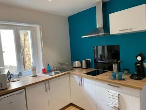 eine Küche mit weißen Schränken und einer blauen Wand in der Unterkunft Esprit Studio sur plateau central in Clermont-Ferrand