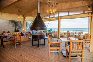 a restaurant with tables and chairs and a view of the ocean at Kara Kedi Beach Bungalow in Cıralı