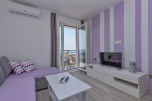 a living room with a purple couch and a tv at Apartments Nataly with FREE PARKING in Makarska